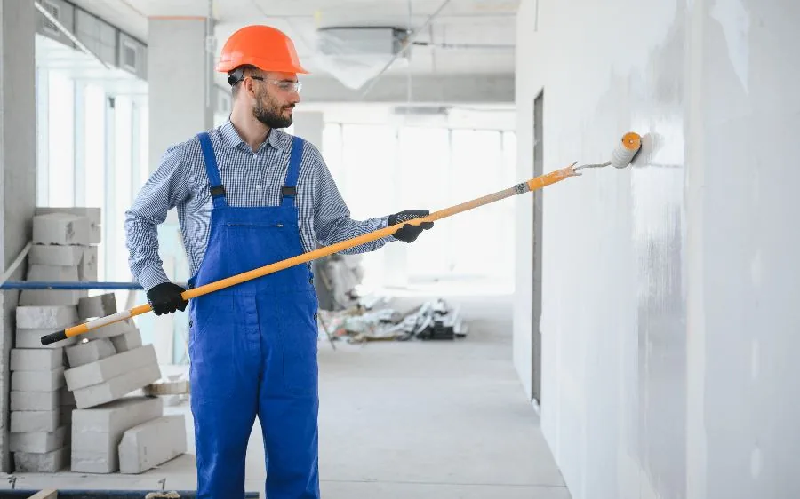 Commercial painting contractor rolling primer onto a new office wall beside floor-to-ceiling windows, Fort Lauderdale, FL