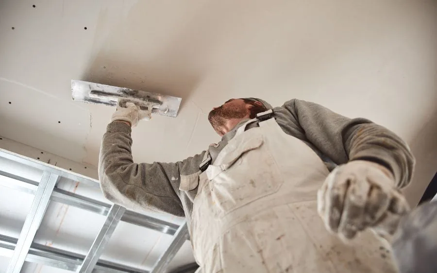 Painter skim coating a drywall ceiling patch with a wide trowel, Delray Beach, FL