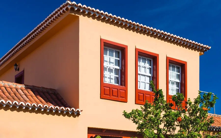 Spanish-style home exterior painting in warm terracotta with red painted window trim and barrel tile roof, Boca Raton, FL