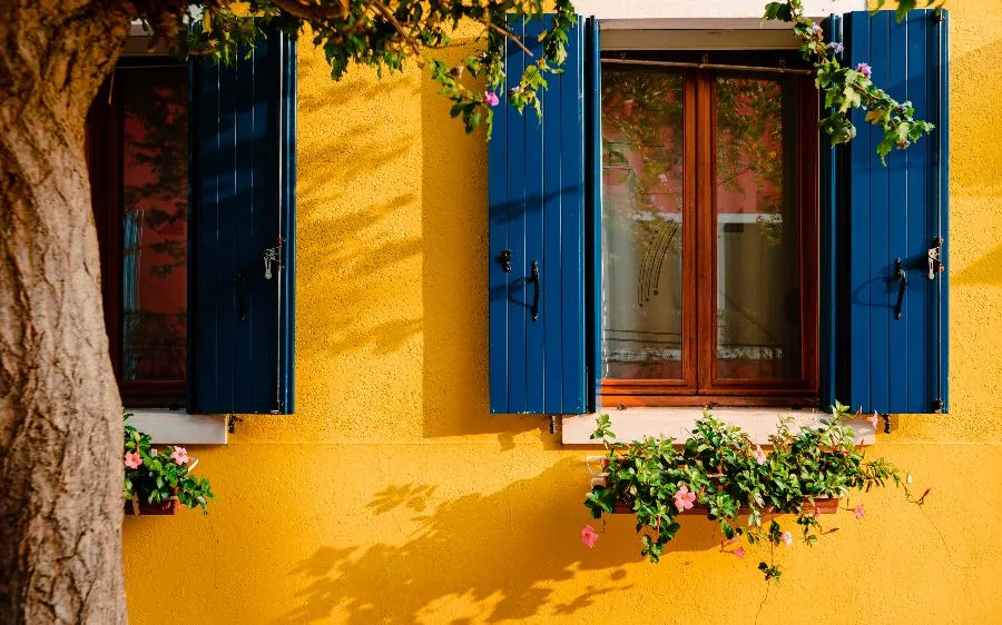 Yellow textured stucco exterior with freshly painted navy blue shutters and white window sills, Delray Beach, FL